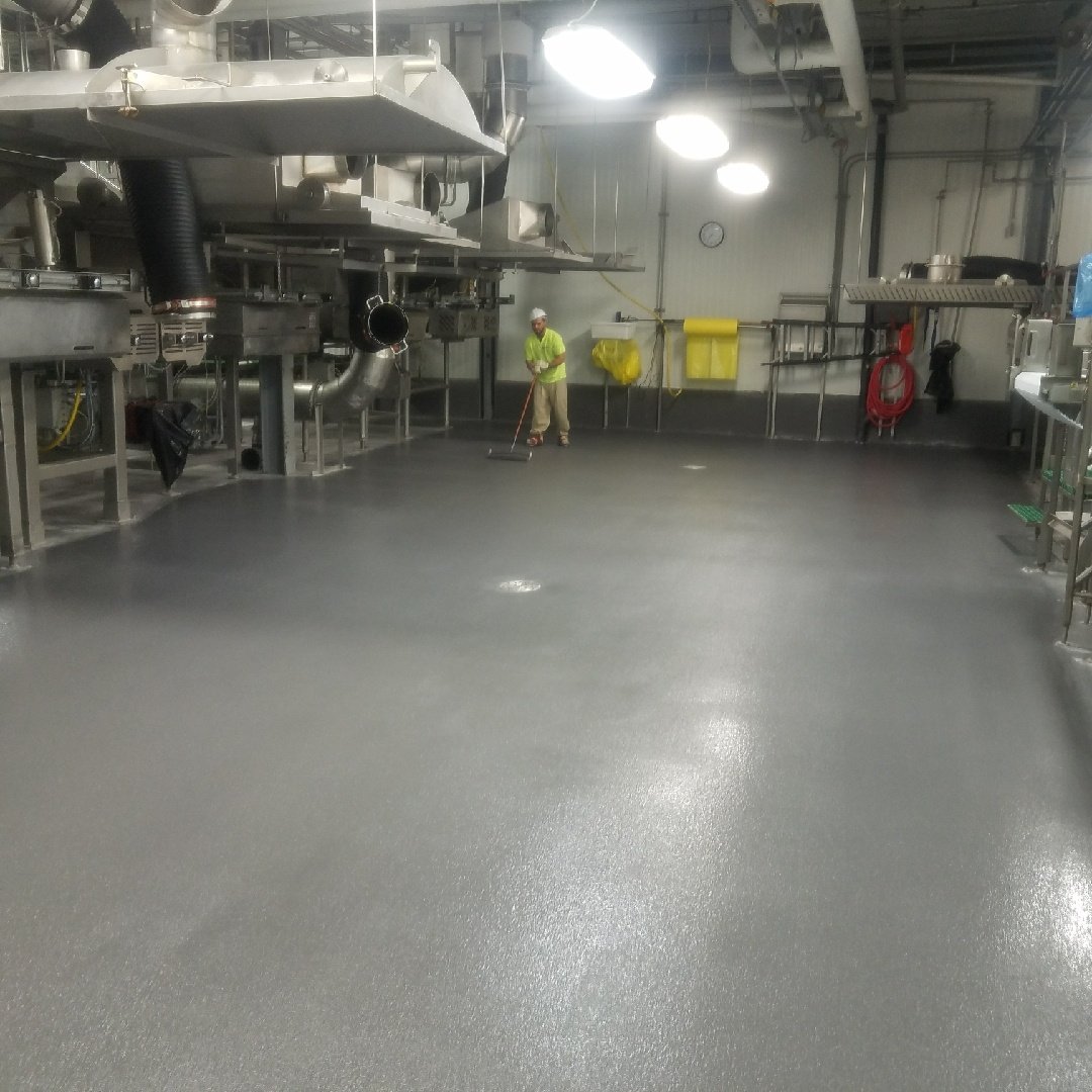 customcrete worker installs a grey Urethane Cement aka polyurethane aka urethane concrete floor in a kitchen