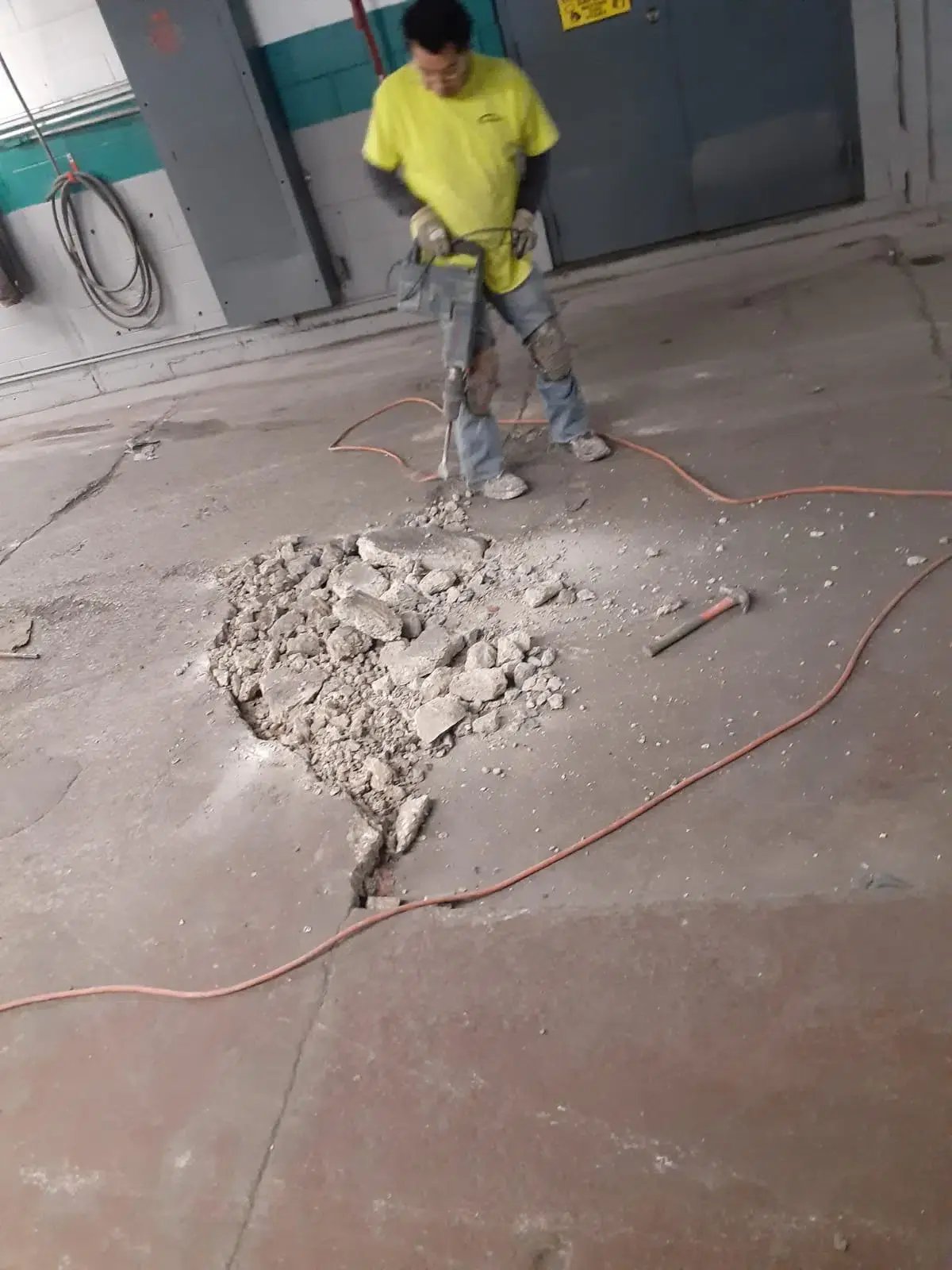 customcrete worker uses a jackhammer to prepare a floor for treatment