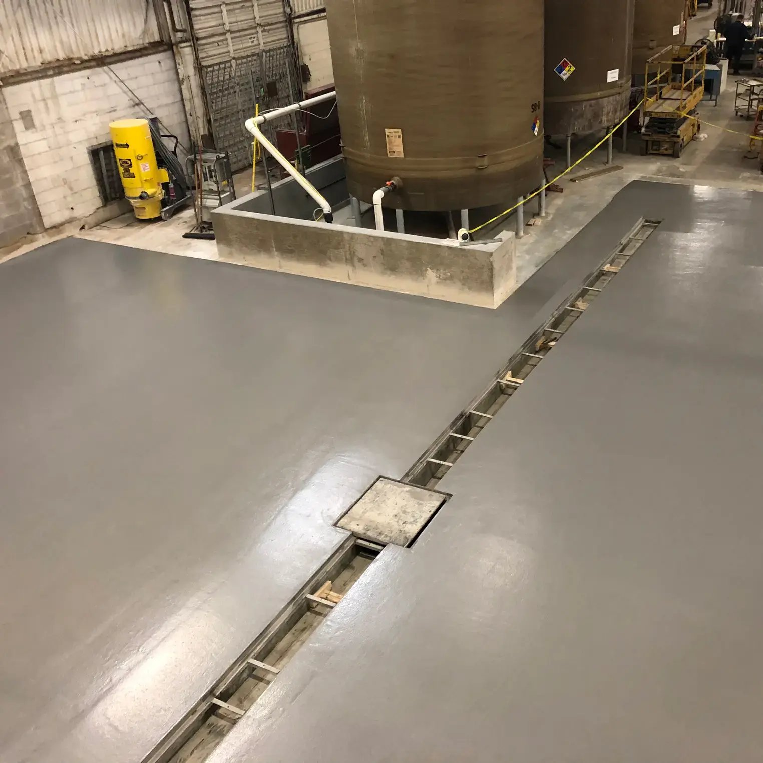 grey Urethane Cement floor with drainage in a food plant with large storage drums.