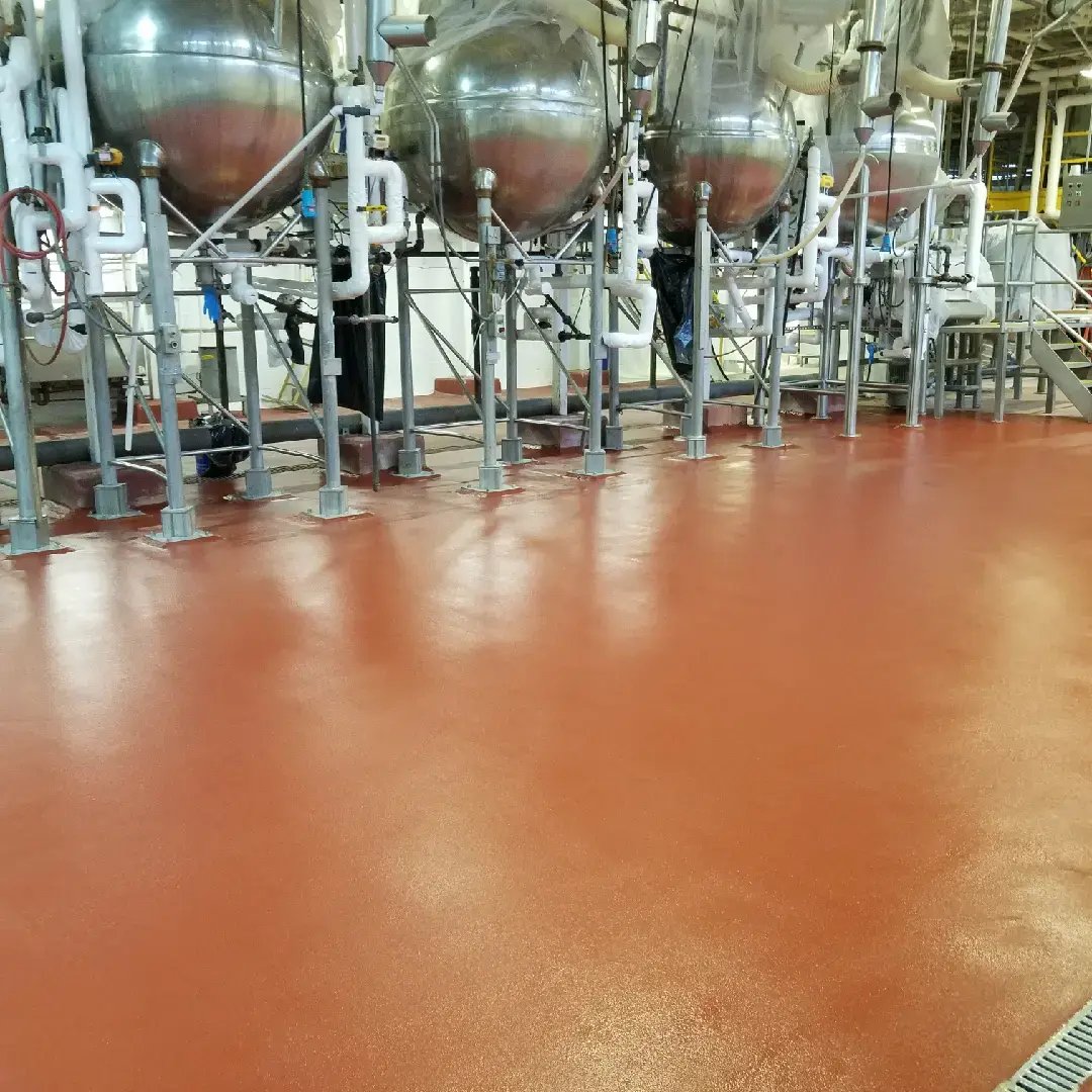 red textured urethane Cement flooring in a food plant/ brewery with large fermentation tanks in backgorund