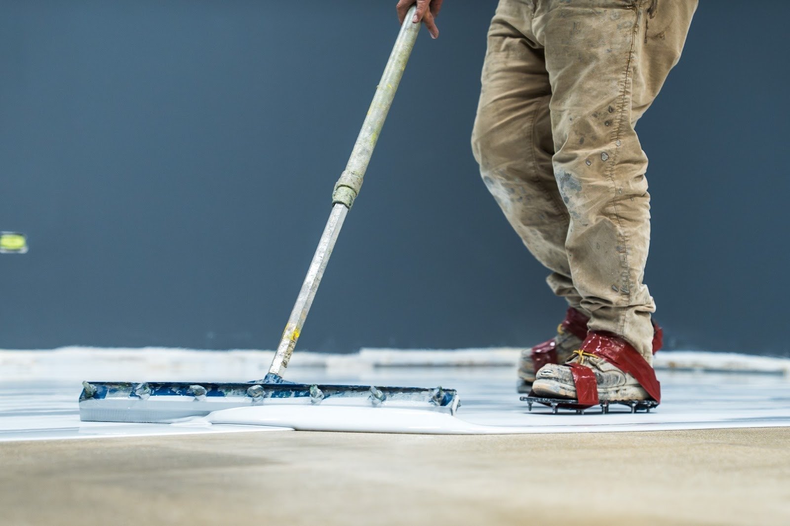 A squeegee applying epoxy to concrete flooring